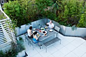 CONTEMPORARY FORMAL ROOF TERRACE/ GARDEN DESIGNED BY DATA NATURE ASSOCIATES: VIEW DOWN ONTO GARDEN WITH SEATING AND DINING AREA. PEOPLE EATING EVENING MEAL AT LARGE TABLE.