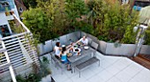 CONTEMPORARY FORMAL ROOF TERRACE/ GARDEN DESIGNED BY DATA NATURE ASSOCIATES: VIEW DOWN ONTO GARDEN WITH SEATING AND DINING AREA. PEOPLE EATING EVENING MEAL AT LARGE TABLE.