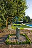 DAVID HARBER SUNDIALS: ARMILLARY SPHERE SUNDIAL ON STONE PATIO WITH CHAIR AND SWIMMING POOL TO THE RIGHT