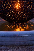 DAVID HARBER. WATER FEATURE: CLOSE UP OF DARK PLANET GARDEN SPHERE LIT UP AT NIGHT
