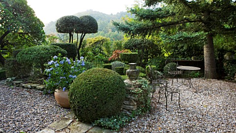 PROVENCE__FRANCE_GARDEN_OF_NICOLE_DE_VESIAN__LA_LOUVE_GRAVEL_TERRACE_WITH_METAL_TABLE_AND_CHAIRS_AND