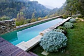 PROVENCE  FRANCE: GARDEN OF NICOLE DE VESIAN  LA LOUVE: SWIMMING POOL WITH STONE SURROUND AND CLIPPED DOMES OF ARTEMISIA  ROSEMARY & HELICHRYSUM (DRY PLANTING)