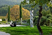 PROVENCE  FRANCE: DOMAINE DE LA VERRIERE: WOODEN SCULPTURES BY MARC NUCERA WITH LINDEN TREE BEHIND