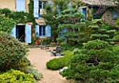 GARDEN OF ERIK BORJA  FRANCE: JAPANESE/ ASIAN STYLE - VIEW TO THE EAST SIDE OF THE HOUSE WITH BLUE SHUTTERS  GRAVEL GARDEN  ROCKS  CLIPPED SCOTS PINE