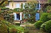 GARDEN OF ERIK BORJA  FRANCE: JAPANESE/ ASIAN STYLE - VIEW TO THE EAST SIDE OF THE HOUSE WITH BLUE SHUTTERS  POLL/ POND  GRAVEL GARDEN  ROCKS  CLIPPED SCOTS PINE
