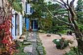 GARDEN OF ERIK BORJA  FRANCE: JAPANESE/ ASIAN STYLE - VIEW TO THE EAST SIDE OF THE HOUSE WITH BLUE SHUTTERS  PATH WITH PEBBLES AND ROCKS  GRAVEL GARDEN  CLIPPED SCOTS PINE
