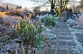 WOLLERTON OLD HALL  SHROPSHIRE: WINTER GARDEN IN FROST -  VIEW ACROSS LANHYDROCK GARDEN AT DAWN WITH STONE PATH AND FROSTED BORDER PLANTS