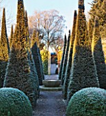 WOLLERTON OLD HALL  SHROPSHIRE: WINTER GARDEN IN FROST -  THE WELL GARDEN WITH CENTRAL LIMESTONE WELL HEAD WATER FEATURE SURROUNDED BY CLIPPED TOPIARY PYRAMID YEWS