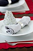 CHRISTMAS TABLE SETTING - NAPKIN AND SILVER DECORATION ON A WHITE PLATE. SARAH EASTEL LOCATIONS/ DI ABLEWHITE