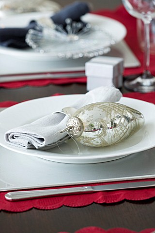CHRISTMAS_TABLE_SETTING__NAPKIN_AND_SILVER_BAUBLE_DECORATION_ON_A_WHITE_PLATE_SARAH_EASTEL_LOCATIONS