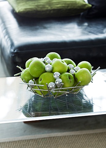 CHRISTMAS__METAL_DISH_WITH_APPLES_AND_SILVER_BAUBLES_ON_GLASS_COFFEE_TABLE_IN_LOUNGE_SARAH_EASTEL_LO