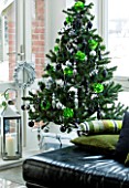 CHRISTMAS - CHRISTMAS TREE WITH PRESENTS IN THE LOUNGE. BLACK LEATHER SOFA  STORM LANTERN AND LIME GREEN CUSHIONS. SARAH EASTEL LOCATIONS/ DI ABLEWHITE