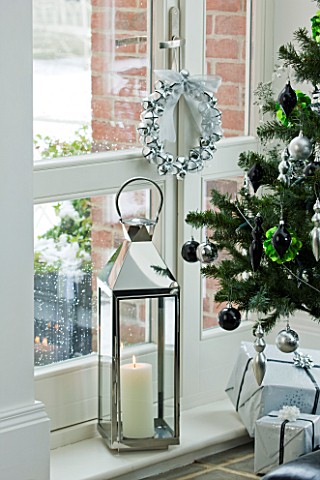 CHRISTMAS__DETAIL_OF_CHRISTMAS_TREE_WITH_BAUBLES_AND_DECORATIONS__STORM_LANTERN_BY_WINDOWSILL_SARAH_