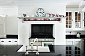CHRISTMAS -DETAIL OF BLACK COOKER AND WHITE WALLS IN THE KITCHEN  CLOCK ON WALL. SARAH EASTEL LOCATIONS/ DI ABLEWHITE