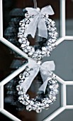 CHRISTMAS - WREATH ON FRONT DOOR MADE WITH SILVER BAUBLES AND TIED RIBBON. SARAH EASTEL LOCATIONS/ DI ABLEWHITE