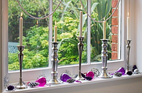 CLARE_MATTHEWS_CHRISTMAS_HOUSE_INTERIOR_WINDOWSILL_DECORATED_WITH_SILVER_CANDLES__BAUBLES_AND_SILVER