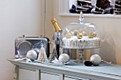 CLARE MATTHEWS CHRISTMAS HOUSE INTERIOR: DRESSER WITH SILVER RADIO  CHAMPAGNE BOTTLE  CHRISTMAS CAKE  SILVER BAUBLES WITH RIBONS