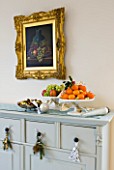 CLARE MATTHEWS CHRISTMAS HOUSE INTERIOR: DRESSER WITH OIL PAINTING  ORANGES  GRAPES AND NUTS IN BOWLS  SILVER BAUBLES