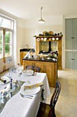 CLARE MATTHEWS CHRISTMAS HOUSE INTERIOR: THE KITCHEN DECORATED FOR CHRISTMAS WITH TABLE AND AGA IN THE BACKGROUND