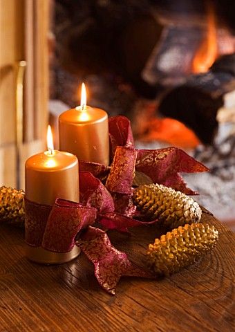 CLARE_MATTHEWS_CHRISTMAS_HOUSE_INTERIOR_THE_LIVING_ROOM__CANDLES_ON_WOODEN_TABLE_WITH_RED_RIBBON_AND