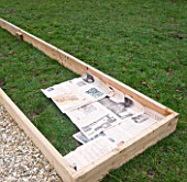 DESIGNER CLARE MATTHEWS: POTAGER PROJECT - DEEP BED MULCHING - NEWSPAPER LAID OUT ON GRASS