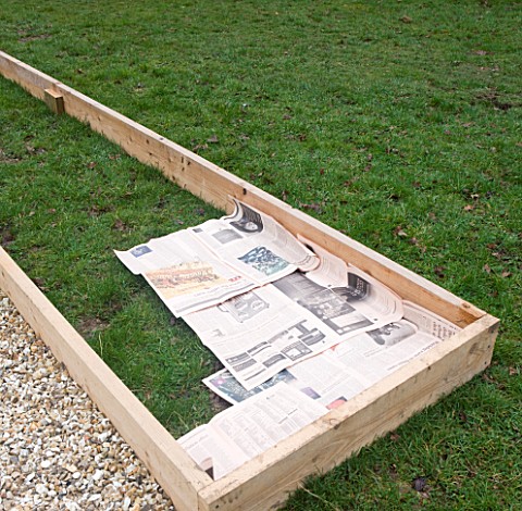 DESIGNER_CLARE_MATTHEWS_POTAGER_PROJECT__DEEP_BED_MULCHING__NEWSPAPER_LAID_OUT_ON_GRASS