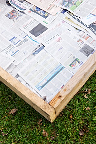 DESIGNER_CLARE_MATTHEWS_POTAGER_PROJECT__DEEP_BED_MULCHING__NEWSPAPER_LAID_OUT_ON_GRASS