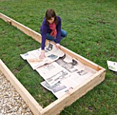 DESIGNER CLARE MATTHEWS - POTAGER PROJECT - CLARE LAYS OUT NEWSPAPER FOR DEEP BED MULCHING