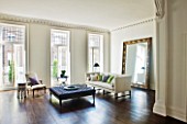 DESIGNER: JOHN MINSHAW - THE SITTING ROOM WITH WOODEN FLOOR  SETTEE  CUSHIONS AND MASSIVE MIRROR BESIDE THE WALL