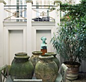 DESIGNER: JOHN MINSHAW - THE BASEMENT - THE BASEMENT GARDEN WITH TABLE AND TERRACOTTA CONTAINERS  BUST ON PEDESTAL