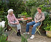 ROSE GRAY AND SCULPTOR DAVID MACILWAINE SITTING AT A TABLE ON THE DECKED ROOF TERRACE/ ROOF GARDEN