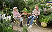 ROSE GRAY AND SCULPTOR DAVID MACILWAINE SITTING AT A TABLE ON THE DECKED ROOF TERRACE/ ROOF GARDEN