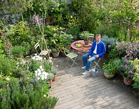 SCULPTOR_DAVID_MACILWAINE_SITTING_AT_A_TABLE_ON_THE_DECKED_ROOF_TERRACE_ROOF_GARDEN