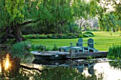 ULTING WICK  ESSEX: SPRING - A PLACE TO SIT - DECKED TERRACE BESIDE THE LAKE WITH ADIRONDACK WOODEN CHAIRS/ SEATS AND BOAT