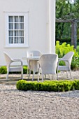 ULTING WICK  ESSEX  SPRING: A PLACE TO SIT - THE WHITE HOUSE WITH WHITE TABLE AND WICKER CHAIRS SURROUNDED BY GRAVEL AND CLIPPED BOX