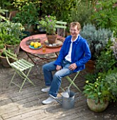 ROSE GRAYS GARDEN  LONDON: SCULPTOR DAVID MACILWAINE SITTING AT A TABLE ON THE DECKED ROOF TERRACE/ ROOF GARDEN