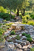 PRIVATE VILLA  CORFU  GREECE. DESIGN BY ALITHEA JOHNS - STONE AND GRAVEL PATH THROUGH WOODLAND WITH STONE BENCH/SEAT
