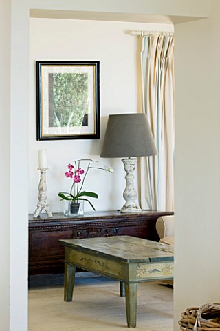THE_KAPARELLI_ESTATE__CORFU__DETAIL_OF_SNUGTV_ROOM_WITH_COFFEE_TABLE_AND_LAMP_ON_WOODEN_SIDEBOARD