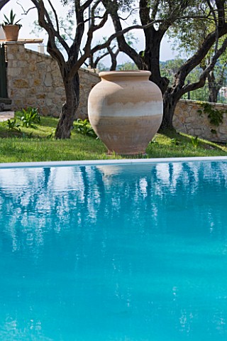THE_KAPARELLI_ESTATE__CORFU__VIEW_OVER_SWIMMING_POOL_TO_OLIVE_TREES_AND_TERRACOTTA_URN