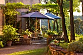 WACHTER HOUSE  FRANCE - TABLE AND PARASOL BEHIND THE HOUSE IN EVENING LIGHT