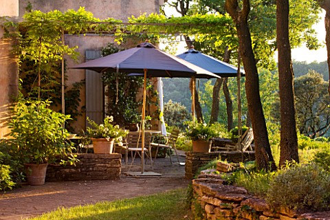 WACHTER_HOUSE__FRANCE__TABLE_AND_PARASOL_BEHIND_THE_HOUSE_IN_EVENING_LIGHT