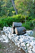 JACQUELINE MORABITO  FRANCE - HUGE LOGS PILED ON STONE WALL TO MAKE A SCULPTURE