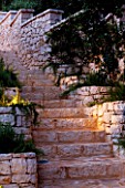 CORFU  GREECE: DESIGNER: DOMINIC SKINNER - MEDITTERANEAN STYLE GARDEN  - BEAUTIFUL STONE STEPS AND WALL LIT UP AT NIGHT  LIGHTING
