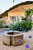 THE ROU ESTATE  CORFU  GREECE: DESIGNER: DOMINIC SKINNER - MEDITTERANEAN STYLE GARDEN - GRAVEL PATH  AGAPANTHUS AND THE WELL