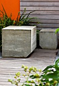 DESIGNERS WYNNIAT- HUSEY CLARKE: MODERN  CONTEMPORARY TOWN GARDEN IN BRIGHTON - CONCRETE SEATS ON DECKING WITH WOODEN PANEL WALLS AND ORANGE PANEL