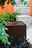DESIGNERS WYNNIAT- HUSEY CLARKE: MODERN  CONTEMPORARY TOWN GARDEN IN BRIGHTON - SQUARE METAL WATER FEATURE  CONCRETE SEATS ON DECKING WITH WOODEN PANEL WALLS AND ORANGE PANEL