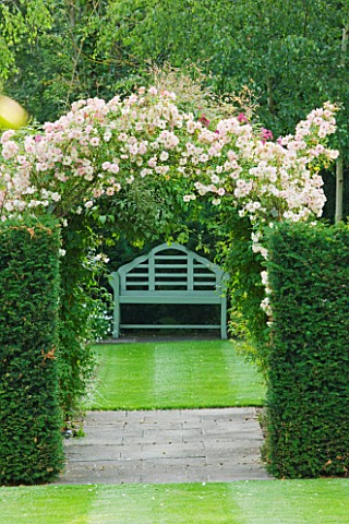 MEADOW_FARM__WORCESTERSHIRE__A_PLACE_TO_SIT__YEW_HEDGES_WITH_LUTYENS_BENCH_BENEATH_ROSE_PHYLLIS_BIDE