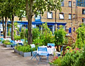 THE RIVER CAFE RESTAURANT  LONDON: GARDEN - BLUE TABLES AND CHAIRS IN BETWEEN RAISED BEDS IN THE VEGETABLE GARDEN WITH THE RESTAURANT BEHIND