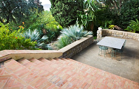 DESIGNER_JEANLAURENT_FELIZIA__FRANCE_BRICK_STEPS_DOWN_TO_PATIO_WITH_TABLE_AND_CHAIRS_LOW_WALL_WITH_B