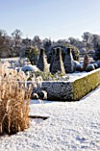 PETTIFERS  OXFORDSHIRE: GARDEN IN SNOW IN WINTER - VIEW TOWARDS THE PARTERRE WITH CLIPPED TOPIARY SHAPES AND THE COUNTRYSIDE BEYOND